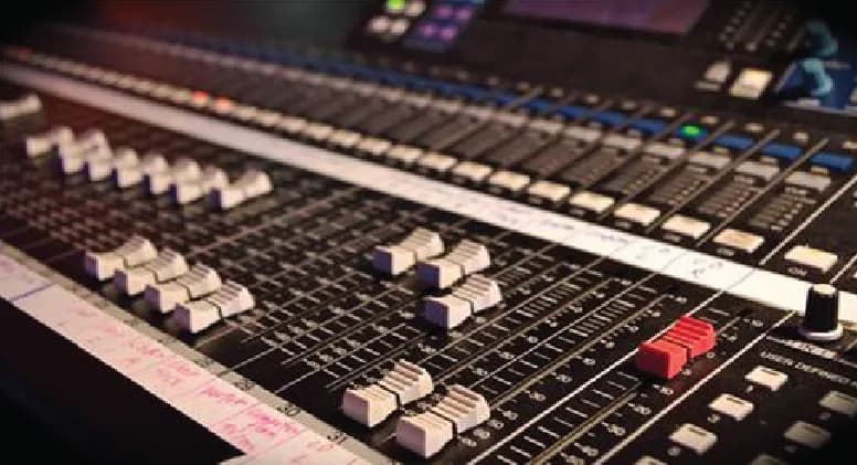 Faders on the front of house mixing desk, labeled with tape